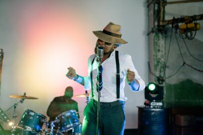 Man in White Shirt and Hat Standing and Singing
